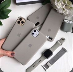 two iphone cases sitting on top of a table next to an apple watch and flowers