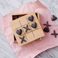 a wooden tic - tacquet with hearts and crosses on it next to other pieces of wood