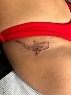 a woman's stomach with a small tattoo of a shark on the lower side