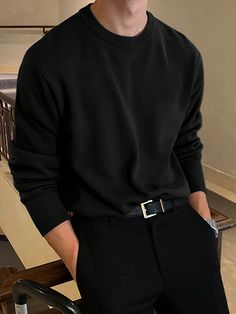 a young man wearing a black sweater and slacks