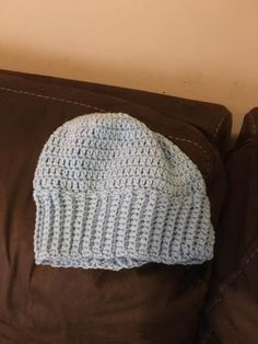 a crocheted hat sitting on top of a brown couch