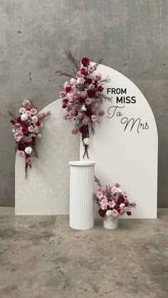 two white vases filled with flowers next to a sign that says from miss to mrs