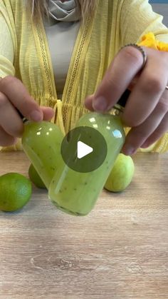 a woman is making a green smoothie with limes on the table next to her