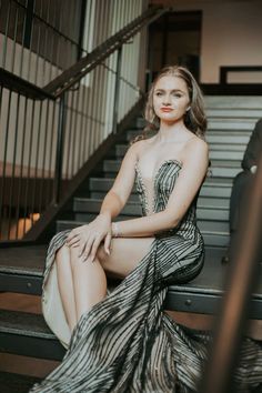 a woman sitting on top of a stair case next to a hand rail and stairs