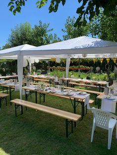 an outdoor dining area with tables, chairs and umbrellas set up in the grass