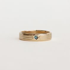 a gold ring with a blue stone in the center and two thin bands around it