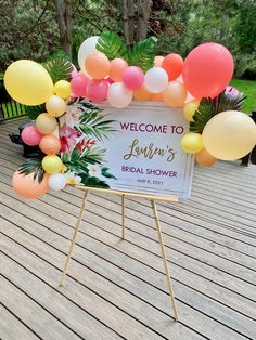 a welcome sign is decorated with balloons and greenery for a tropical bridal shower