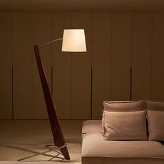 a living room with a couch, lamp and wooden paneled wall in the background