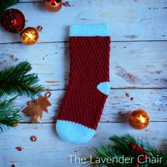 a red and blue knitted sock sitting on top of a wooden table next to christmas decorations