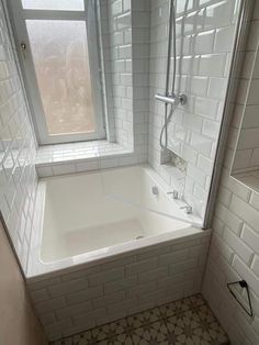 a bath tub sitting next to a window in a bathroom