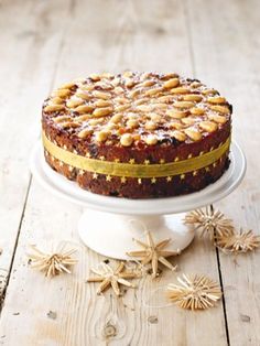 a cake sitting on top of a white plate covered in frosting and gold sprinkles