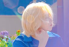 a young blonde boy sitting in front of flowers