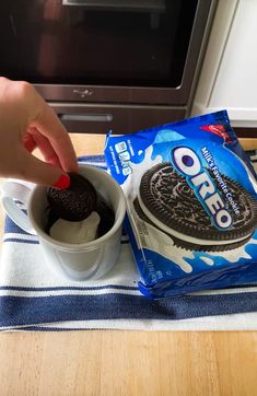 A hand dipping an Oreo into a mug filled with the beginnings of an Oreo mug cake, with a package of Oreos resting on a kitchen countertop nearby. Mug Cake Tiktok, Oreo Fluff Dessert, Oreo Mug Cake, Oreo Mug, Cake Microwave, Oreo Milk, Cake Oreo, Red Birthday Cakes, Recipe Tiktok