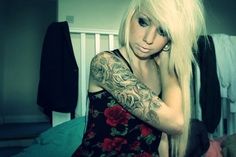 a woman with long blonde hair and tattoos on her arm is posing for the camera