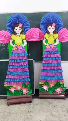 two paper dolls are standing in front of a blackboard