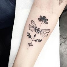 a black and white photo of a dragonfly tattoo on the left arm with flowers