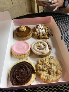 a pink box filled with lots of different types of cookies and pastries on top of a table