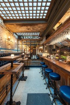 the inside of a restaurant with blue stools and wooden tables in front of it