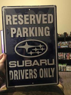 a black and white sign that says reserved parking subaru drivers only in front of a bookshelf