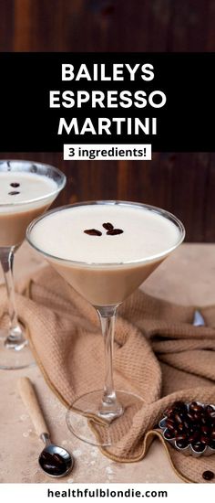 two glasses filled with drinks sitting on top of a table next to some spoons