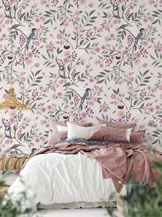 a bed sitting under a pink wallpaper covered in lots of leaves and flowers next to a potted plant