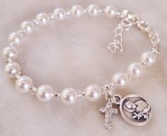 Celebrate the baptism of a baby girl with this beautiful white Swarovski pearls size 5. Bracelet length 14cm Extension 2.5cm. Brass and diamonties cross. please refer to drop down menu to choose your charm 1- Devine Jesus  2-Saint Girad Custom orders are available, please contact me to discuss anything you have in mind. Keep in mind a matching rosary is available on your request. Made in Australia, pearls are genuine Swarovski made in Austria. Please make sure to store item in packaging when not Silver Adjustable Rosary Bracelet For Wedding, Adjustable Silver Pearl Bracelet For Baptism, Elegant Personalized Jewelry For Confirmation, Silver Name Bracelet With Birthstone For Wedding, Personalized White Charm Bracelet For Anniversary, Silver Wedding Name Bracelet With Birthstone, Elegant White Bracelets, Classic White Charm Bracelet As Gift, White Round Bead Bracelets For Baptism