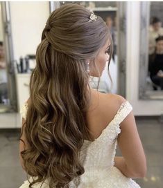 the back of a woman's head with long, wavy hair and blue earrings