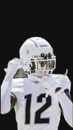 a football player wearing a white uniform and holding his hands in the air