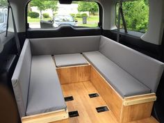 the inside of a van with two seats and storage drawers on the back wall,