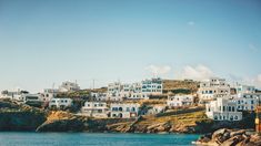 the white houses are on top of the hill by the water in front of them