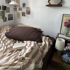 a bed sitting in a bedroom next to a wall with pictures on it and flowers