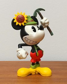 a mickey mouse figurine holding a baseball bat on top of a wooden table