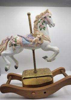 a toy rocking horse with a gold plate on it's back and pink flowers on its tail