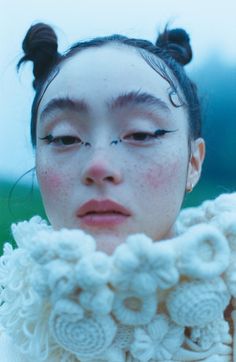 a woman with freckles on her face wearing a white sweater and flowered scarf