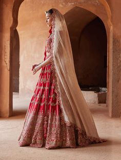 Editor's Note Embrace allure in our scarlet red raw silk lehenga choli set. The scalloped net dupatta is a masterpiece, adorned with delicate 3D flowers intricately embroidered in gold zari, dabka, sequins, beadwork, and crystals. This ensemble harmonizes traditional craftsmanship and contemporary elegance, capturing attention with its exquisite details and luxurious flair. Note: Gold veil dupatta is for styling purposes only. Fabric: Raw silk and net Color: Red Components: Lehenga, blouse and d Bridal Clothes, Gold Veil, Bridal Lehenga Online, Silk Lehenga Choli, Raw Silk Lehenga, Bridal Lehenga Collection, Crystal Embroidery, Designer Bridal Lehenga, Bridal Lehenga Red