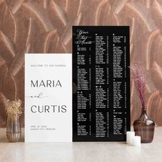 a black and white wedding seating chart next to two vases