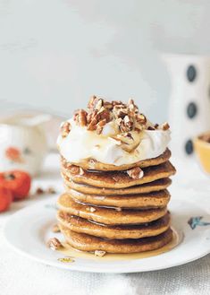 a stack of pancakes topped with whipped cream and walnuts