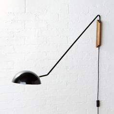 a black lamp on a white brick wall with a wooden stick attached to the light