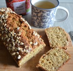 a loaf of bread sitting on top of a cutting board next to a cup of tea