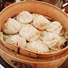 a wooden basket filled with dumplings sitting on top of a table