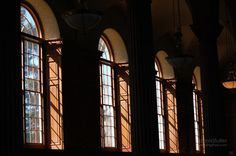 the sun shines through three windows in an old building