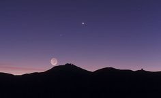 the moon and venus are seen in the night sky over mountain tops, with mountains behind them