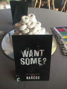 a table topped with donuts covered in frosting next to a book titled want it some?