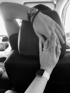 black and white photograph of two people holding hands in the back seat of a car