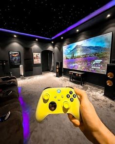 a person holding a video game controller in front of a television screen and couches