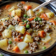 a close up of a bowl of soup with meat, potatoes and carrots in it