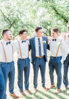 a group of young men standing next to each other in front of trees and grass