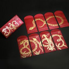 red envelopes with gold designs on them next to a bar of chocolate in the shape of snake