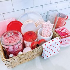 a basket filled with lots of pink and red items on top of a counter next to a white tiled wall