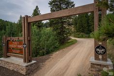 a dirt road with a wooden gate and sign